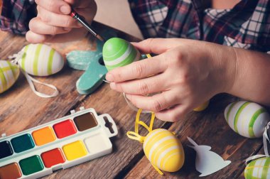 Boya fırçası ve Paskalya yortusu yumurta, rustik ahşap masa DIY kompozisyonu holding Femail eller