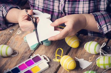 Paskalya tavşanı kağıttan, rustik ahşap masa DIY kompozisyonu kesme eller