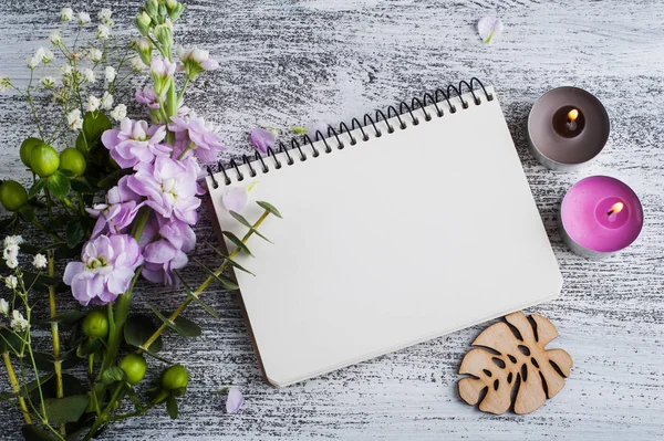 Empty open notepad with flowers and candles