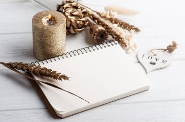 Boş bir defter, altın kuru çiçekler ve dekorasyon için yanan bir mum. Tatil ya da ahşap kalpli düğün organizatörü konsepti