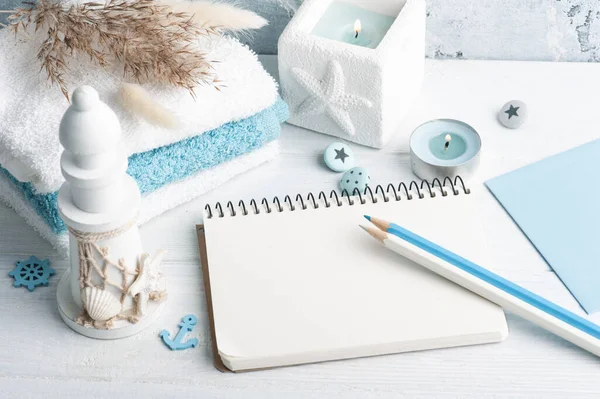 Empty notebook with blue decor and lit candle as decoration. Holiday or wedding planner concept with pencils