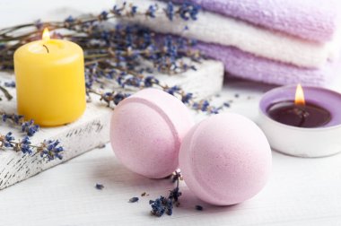 Kuru lavanta çiçekleri ve havlularla kaplıca kompozisyonunda pembe aromalı banyo bombaları. Aromaterapi düzenlemesi, yanan mumlarla dolu bir hayat.