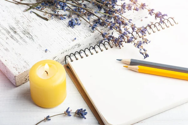 Empty open notebook with dry lavender flowers. Aromatherapy arrangement, zen still life with lit candle