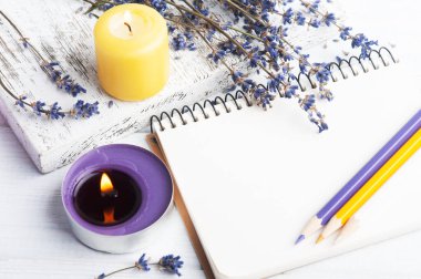 Lavanta çiçekli boş bir defter. Aromaterapi düzenlemesi, yanan mumlarla dolu bir hayat.
