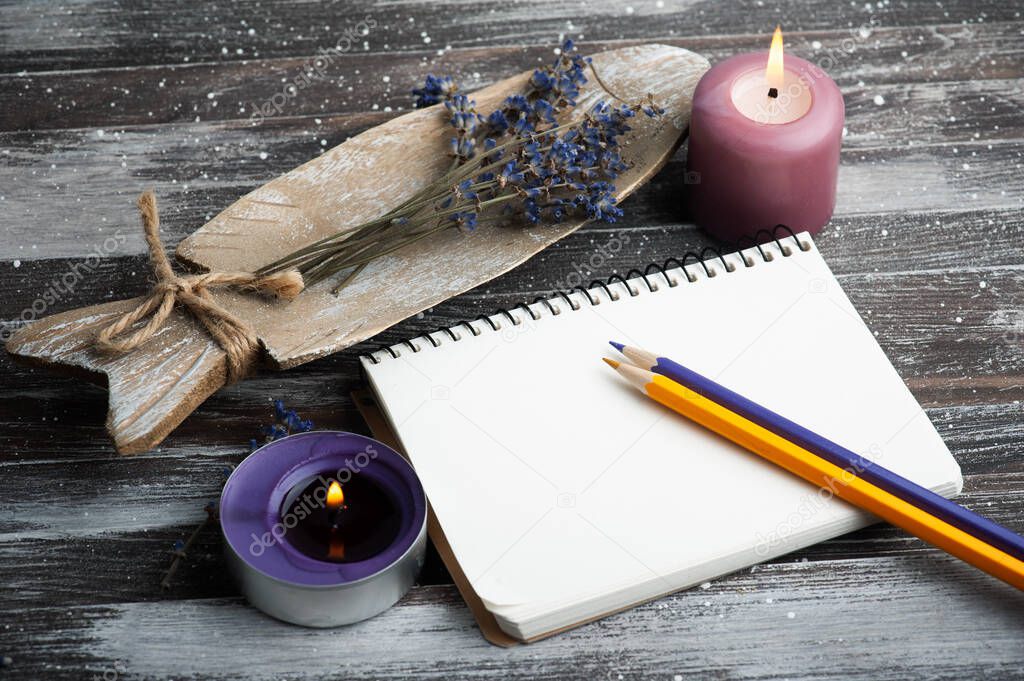 Blank note book, purple aroma candles and dry lavender flowers on wooden rustic background. Summer or autumn set with copy space