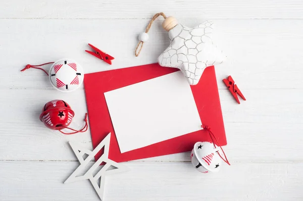 Blank red envelope, empty note and white Christmas toys on wooden rustic background. Winter set with copy space