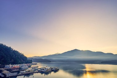 Nantou, Tayvan - 8 Aralık 2018: Sun Moon Gölü'nün çevredeki dağlarıyla birlikte güzel gün doğumu manzaraları, Tayvan'ın Nantou kentinde ki Yuchi'deki bu yayılan gölün en önemli özelliğidir..