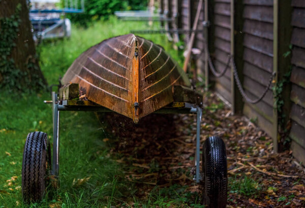Лодка на трейлере. Один старый перевернутый деревянный катер на прицепе в парке на заднем плане в пасмурный день в Лозанне, Швейцария
.