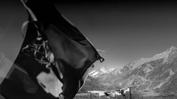 Laundry and flags in mountains. Clothes hanging to dry, flags waving in wind and blue sky in summer in Aosta Valley in Italy. Black and white image.