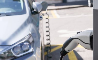 Elektrik kablosu prize takılı olarak şarj istasyonunda EV Car veya elektrikli araba. Çevre dostu alternatif enerji kavramı.