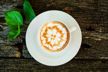 «Ana sayfa» ahşap plaka üzerinde / sıcak sıcak cappuccino görünümünü cappuccino kahve çekirdeği ve ahşap masa üzerinde yeşil yaprak ile