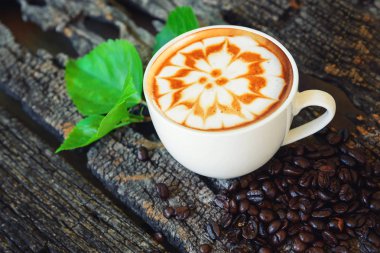 sıcak cappuccino ahşap masa / sıcak cappuccino kahve çekirdeği ve ahşap masa üzerinde yeşil yaprak ile