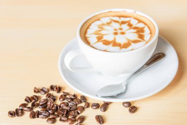 Sıcak kapuçino. Masanın üzerinde köpük desenli güzel bir kahve.