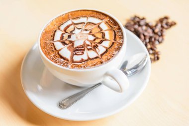 sıcak cappuccino ahşap masa / sıcak cappuccino kahve çekirdeği ve ahşap masa üzerinde yeşil yaprak ile