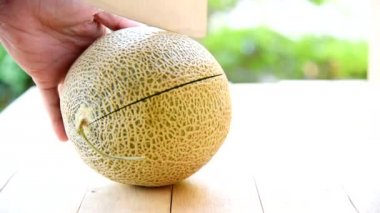 Bıçak kullanan adam portakallı karpuzu ahşap tabakta ikiye böldü.