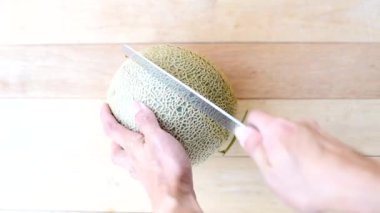 Bıçak kullanan adam portakallı karpuzu ahşap tabakta ikiye böldü.