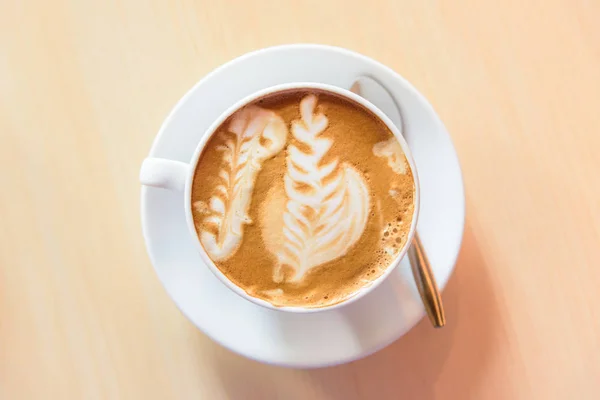 ホット コーヒーを手に手に素敵なパターンとカプチーノをホット 木製の背景 — ストック写真