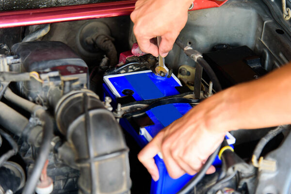 Мужчина перевернул гаечный ключ для замены батареи старого автомобиля
