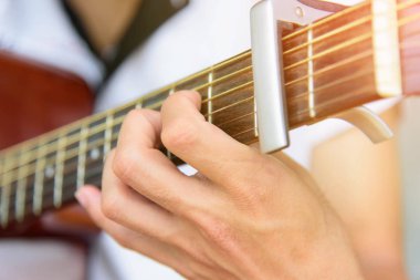 Müzisyen capo ile akustik gitar parmak tarzı oynuyor
