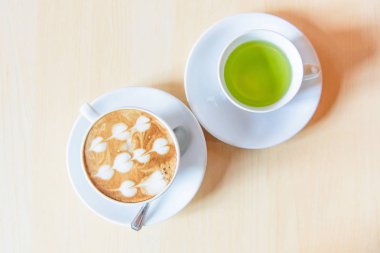 Sıcak kahve, sıcak kapuçino ve güzel desenli süt köpüğü. 