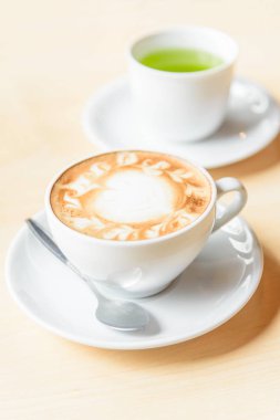 Sıcak kahve, sıcak kapuçino ve güzel desenli süt köpüğü. 