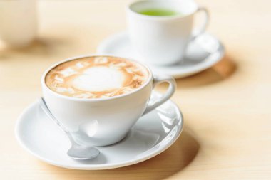 Sıcak kahve, sıcak kapuçino ve güzel desenli süt köpüğü. 