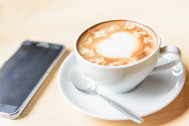 sıcak cappuccino güzel süt desen ve çalışma alanı tablosu Office'te akıllı telefon