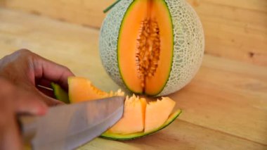 Bıçak kullanan adam portakallı karpuzu ahşap tabakta ikiye böldü.