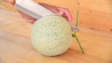 Bıçak kullanan adam portakallı karpuzu ahşap tabakta ikiye böldü.