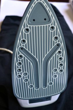 Çamaşır ütülemek için beyaz ve pembe ütü. Tişörtler, kazaklar, eşyalar. Ütü tahtası.