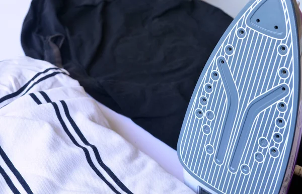 Çamaşır ütülemek için beyaz ve pembe ütü. Tişörtler, kazaklar, eşyalar. Ütü tahtası.