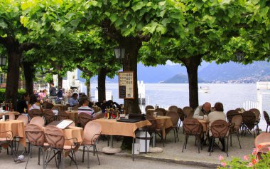 BELLAGIO, İtalya - 23 Mayıs 2013: Illustrative editorial - İnsanlar gölün kenarındaki restoran terasında, Bellagio limanında, Como Gölü, Lombardy, İtalya