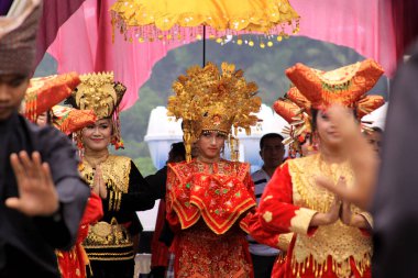 Utangaç geleneksel Minangkabau kadın dansçısı Sumatra, Endonezya 'da kalabalığa bakıyor. Padang 'da halka açık bir törende renkli Minang giysileri giymiş kadınlar.