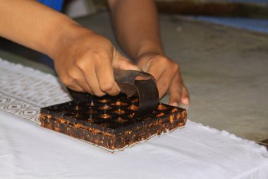 Yogyakarta, Java, Endonezya 'daki Winotosastro fabrikasında Batik Balmumu Pul İşlemi. Batik motif tasarımları kumaş üzerinde. Çiçek tasarım sembollerini tasvir ediyor. Tekstil parçası kurumak üzere.