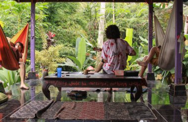 Gitarist rahatlatıcı şarkılar çalar ve iki kişi balya altında hamakta dinlerler, Ubud 'da. Hippi, Ubud, Bali ve Endonezya 'daki dinlenme tesisinde rahat bir atmosfer yarattı. Kilitleme şarkı etkinliği