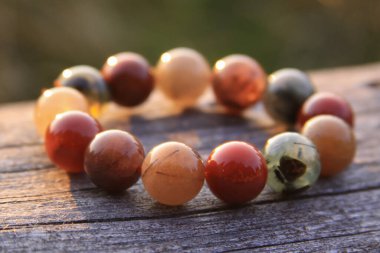 Şeffaf kırmızı, yeşil, turuncu, sarı ve beyaz gibi yuvarlak değerli boncuklardan yapılmış bileklik takılar. Bazıları paslanmış ve turnikelenmiş kuvars..