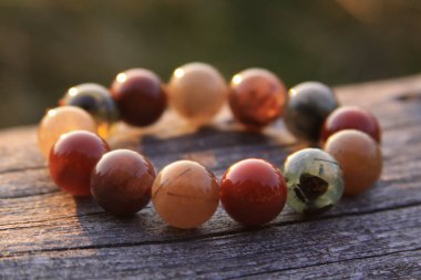 Şeffaf kırmızı, yeşil, turuncu, sarı ve beyaz gibi yuvarlak değerli boncuklardan yapılmış bileklik takılar. Bazıları paslanmış ve turnikelenmiş kuvars..