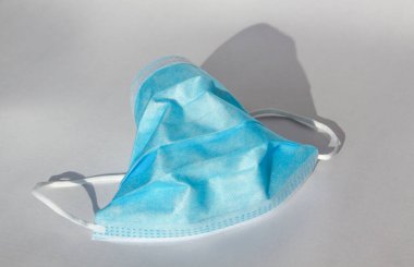 Beyaz arka planda virüs koruması için tek bir mavi tıbbi maske var. Cerrahi maske, 2020 Coronavirus (covid-19) hastalığına karşı bir koruma sembolüdür.
