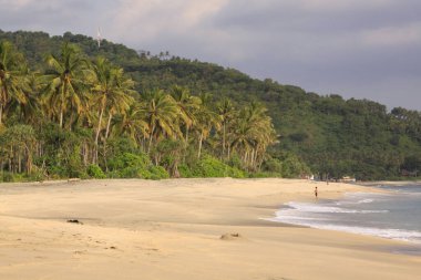 Pantai Setagi 'de, Senggigi, Lombok, Endonezya yakınlarındaki boş plajda tek başına bir kişi. Adadaki egzotik tropikal plaj