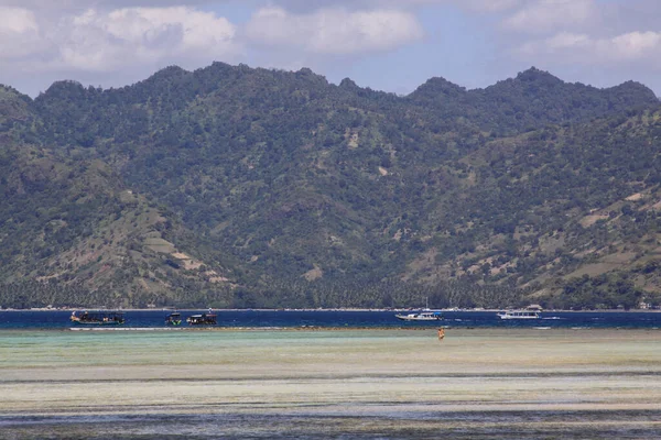 在印度尼西亚伦博克岛的吉里空岛 在低潮的珊瑚礁尽头 渔船和旅游船在浅海中行走的有2个人 — 图库照片
