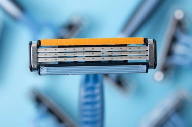 Kapalı çekimli jilet ve alttaki diğer bıçakları mavimsi arkaplanda detaylandır