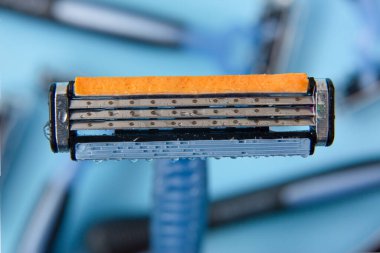 Kapalı çekimli jilet ve alttaki diğer bıçakları mavimsi arkaplanda detaylandır