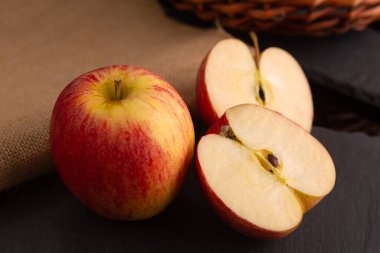 two red apples placed on a piece of slate in a dim light environment clipart