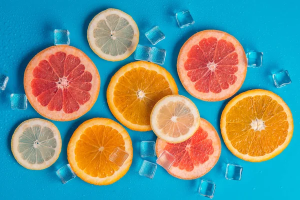 Schijfjes Sinaasappel Grapefruit Citroen Een Blauwe Achtergrond Met Ijs Eromheen — Stockfoto