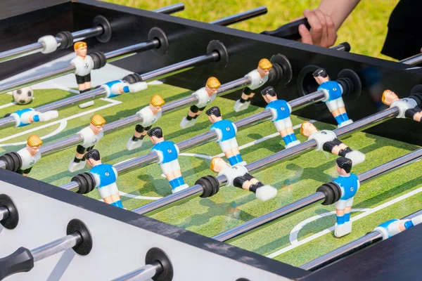 Children play table football in the yard on a sunny day.