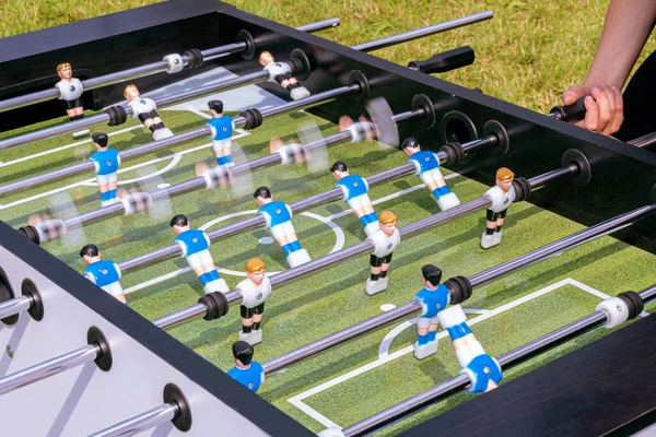 Children play table football in the yard on a sunny day.