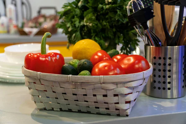 Sepetteki sebzeler mutfak masasındaki şifalı bitkilerin yanında. Stüdyo çekimi.