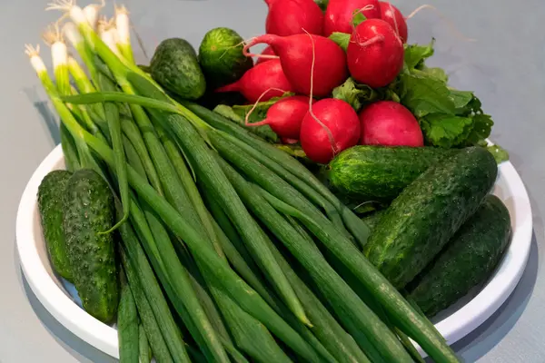 Mutfak masasındaki beyaz tabakta sebzeler. Stüdyo çekimi.