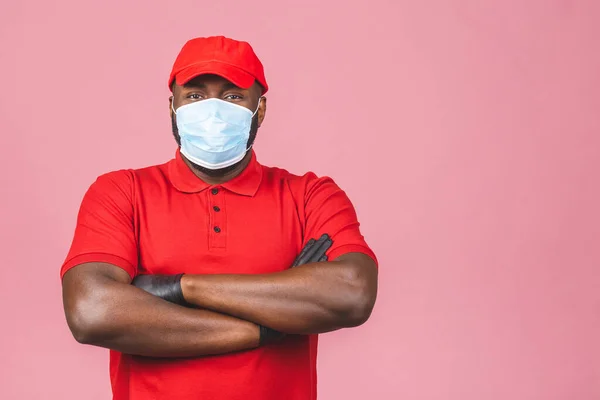 Delivery man in red cap blank t-shirt uniform sterile face mask gloves isolated on pink background. Guy employee working courier Service quarantine pandemic coronavirus virus.