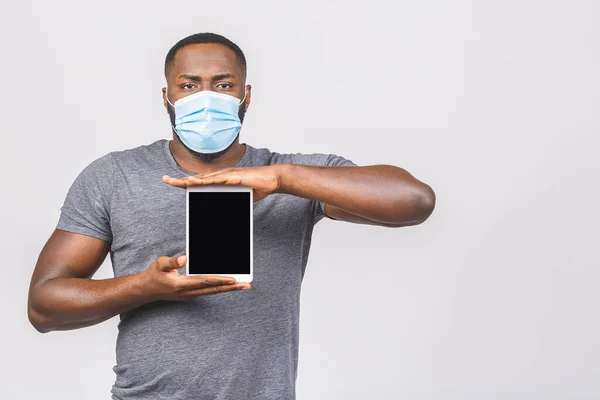 African american man with mask to protect him from Coronavirus. Corona virus pandemic. Person with medical mask. Isolated on white background. Holding tablet computer empty screen frame.